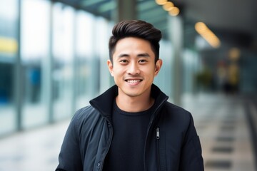 Portrait of a young asian man smiling at the camera outdoors