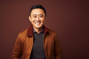 Fototapeta premium Portrait of a smiling asian man in a brown jacket.