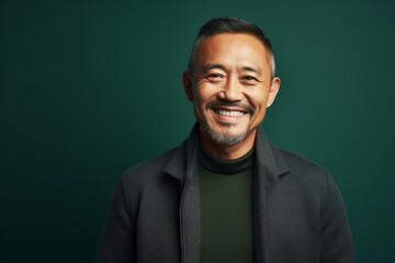 Portrait of smiling asian man looking at camera against green background