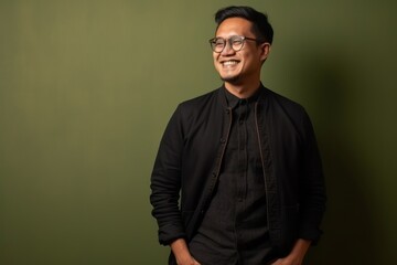 Fototapeta premium Portrait of a young Asian man wearing eyeglasses against green background