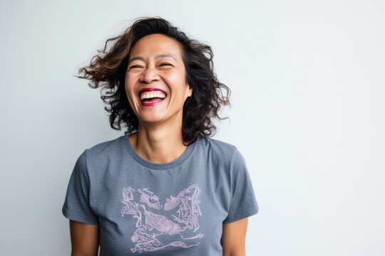 Portrait Of A Beautiful Young Asian Woman Laughing Against White Background