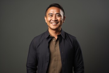 Fototapeta premium Portrait of happy young asian man smiling at camera. Isolated on grey background