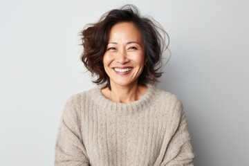 Fototapeta premium Portrait of a Chinese woman in her 40s in a white background wearing a cozy sweater