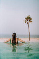 Chica joven delgada posando y descansando en piscina de hotel de lujo en andalucia
