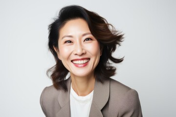 Portrait of a Chinese woman in her 40s in a white background wearing a classic blazer