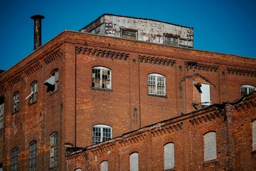 Old run down factory with broken windows against a clear blue sky