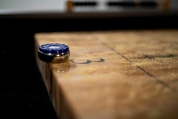 Selective focus shot of a puck on the edge of the table shuffleboard