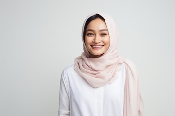 Portrait of asian muslim woman wearing hijab smiling at camera over white background