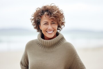 Portrait of smiling middle aged woman with curly hair standing on beach