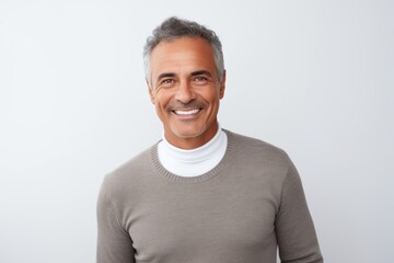 Fototapeta premium Portrait of handsome mature man looking at camera and smiling while standing against white background