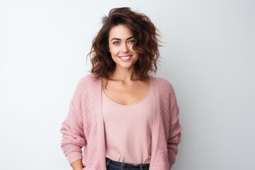 Obraz premium Portrait of a smiling young woman standing with hands in pockets over white background