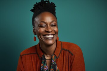 Fototapeta premium Portrait of a beautiful young african american woman laughing against a green background