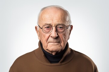 Obraz premium Elderly man with glasses and a brown sweater on a white background