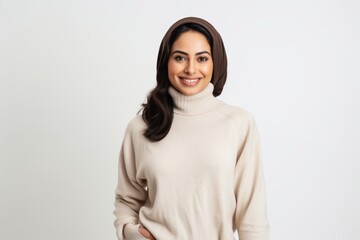Fototapeta premium Portrait of a Saudi Arabian woman in her 30s in a white background wearing a cozy sweater