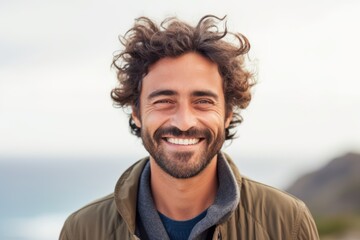 Portrait of a handsome young man smiling at camera on the beach