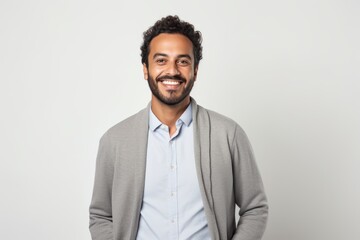 Portrait of a Saudi Arabian man in his 30s in a white background wearing a chic cardigan