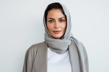 Portrait of a Saudi Arabian woman in her 40s in a white background wearing a chic cardigan