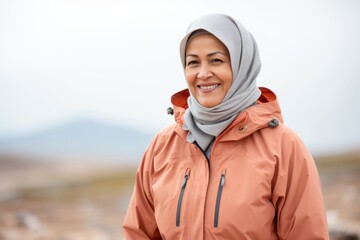 Muslim woman wearing a headscarf smiling at the camera while standing outdoors