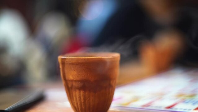 hot beverage like chai tea coffee with smoke coming out in a kullad clay pot which is traditionally used in india and is biodegradable and all natural