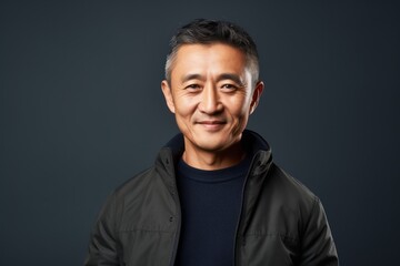Obraz premium smiling asian man in jacket looking at camera isolated on grey