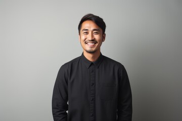 Obraz premium Portrait of a smiling asian man in black shirt on grey background