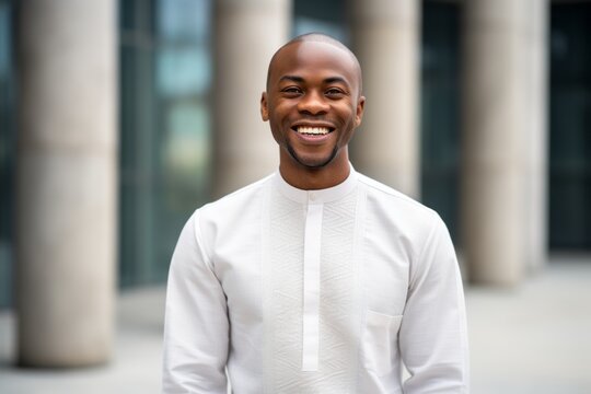 Portrait of a Nigerian man in his 30s in a modern architectural background wearing a simple tunic