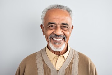 Obraz premium Portrait of happy senior Indian man smiling at camera, isolated on grey background
