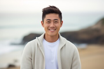 Portrait of a young asian man smiling at the camera on the beach