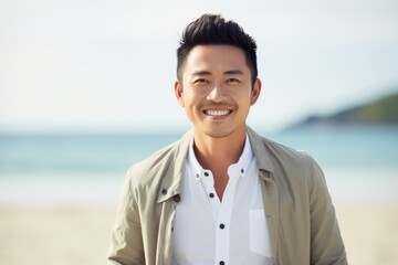 Portrait of happy young man standing on the beach and looking at camera