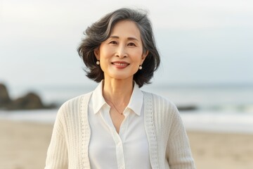 asian senior woman smiling and looking at camera at the seaside