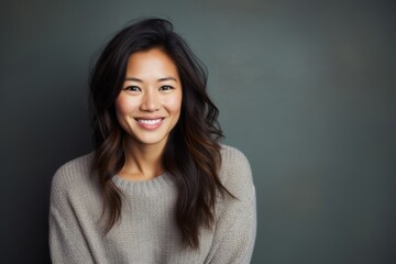 Fototapeta premium Portrait of a Chinese woman in her 30s in an abstract background wearing a cozy sweater