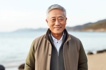Fototapeta premium Portrait of a smiling senior man standing on the beach by the sea
