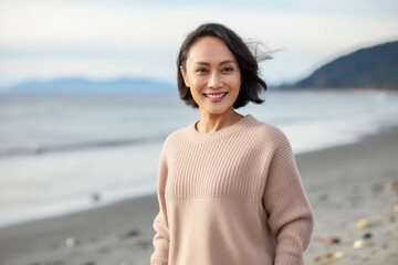 Portrait of smiling young woman standing on the beach at autumn day