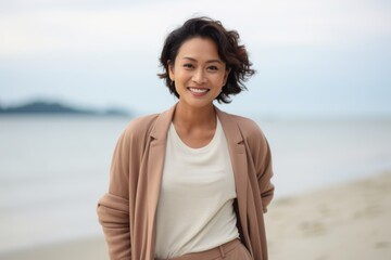 Portrait of happy young woman standing on beach and looking at camera