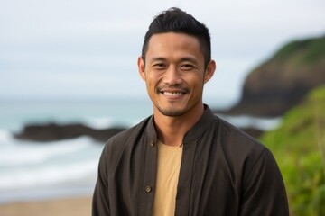 Portrait of young handsome Asian man smiling at camera on the beach