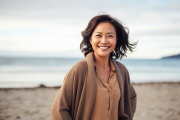 Portrait of happy mature woman smiling at camera on beach during autumn day