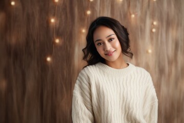 Fototapeta premium Portrait of a Indonesian woman in her 20s in an abstract background wearing a cozy sweater
