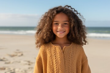 Portrait of smiling little girl with curly hair at beach on a sunny day