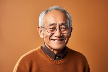 Obraz premium Portrait of a Indonesian man in his 80s in an abstract background wearing a cozy sweater
