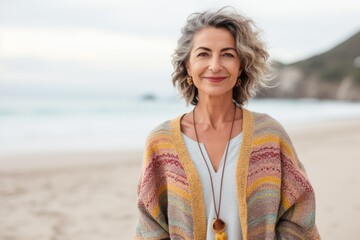 Medium shot portrait of a Brazilian woman in her 50s in a beach background wearing a chic cardigan
