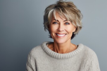 Fototapeta premium Portrait of a Russian woman in her 50s in an abstract background wearing a cozy sweater