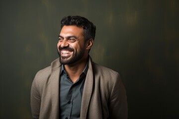 Fototapeta premium Portrait of a Saudi Arabian man in his 30s in an abstract background wearing a chic cardigan