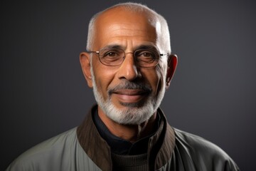 Portrait of a Saudi Arabian man in his 70s in an abstract background wearing a chic cardigan