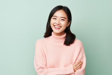 Fototapeta premium Portrait of a Chinese woman in her 30s in a pastel or soft colors background wearing a cozy sweater
