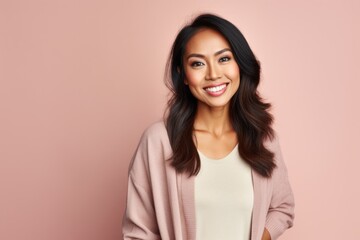 Fototapeta premium Portrait of a Indonesian woman in her 30s in a pastel or soft colors background wearing a chic cardigan