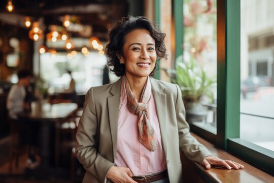Portrait of a Indonesian woman in her 40s in a pastel or soft colors background wearing a classic blazer