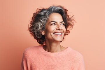 Portrait of a Brazilian woman in her 50s in a pastel or soft colors background wearing a cozy sweater