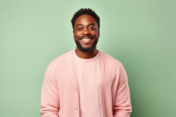 Fototapeta premium Portrait of a Nigerian man in his 30s in a pastel or soft colors background wearing a chic cardigan