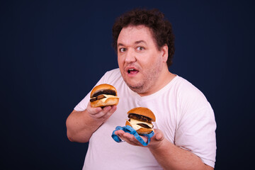 Funny fat man on a diet eats hamburgers.