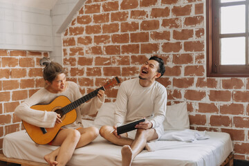 Happy laughing asian couple making lyrics and songs in bedroom a happy day.